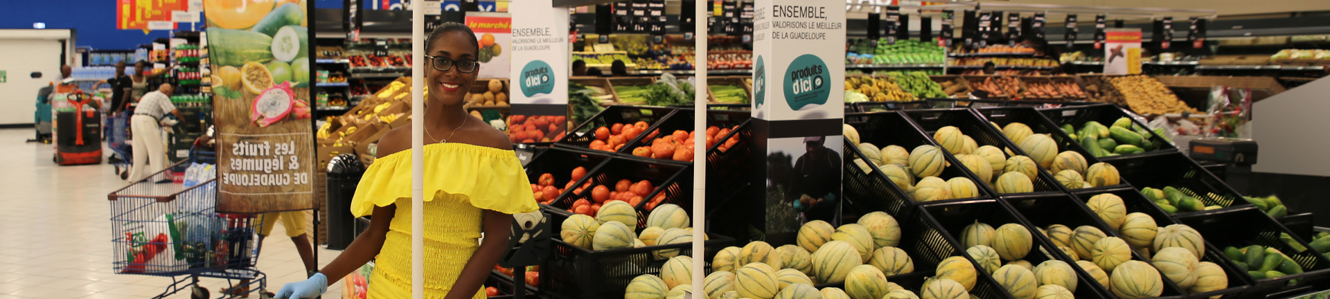 Femme devant des rayons de fruits et légumes locaux dans un supermarché