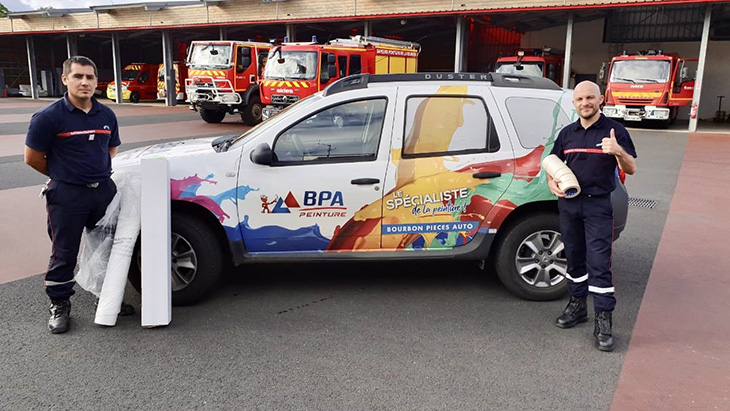 Deux pompiers posant devant une Dacia Duster sponsorisée par BPA Peinture 