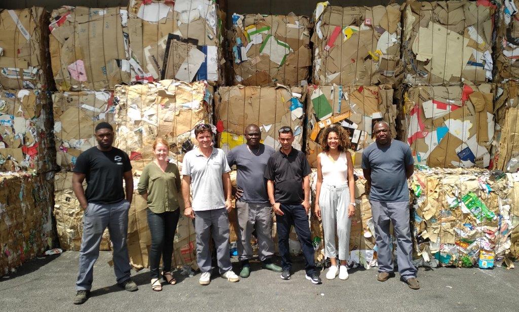 Collaborateurs de Guyane Automobile devant une pile de carton au centre de Tri Ekotri de la commune de Matoury