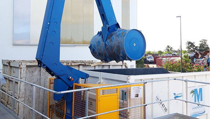 Compacteur à rouleaux écrasant des palettes en bois dans une benne métallique pour le recyclage